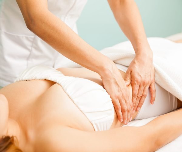 Closeup of the hands of a therapist giving a deep tissue massage to a female client at a spa