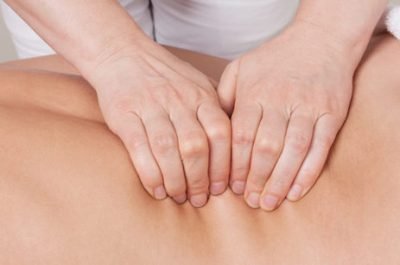 Sport professional massage on a muscle group (erector spinae muscles) of a womans back